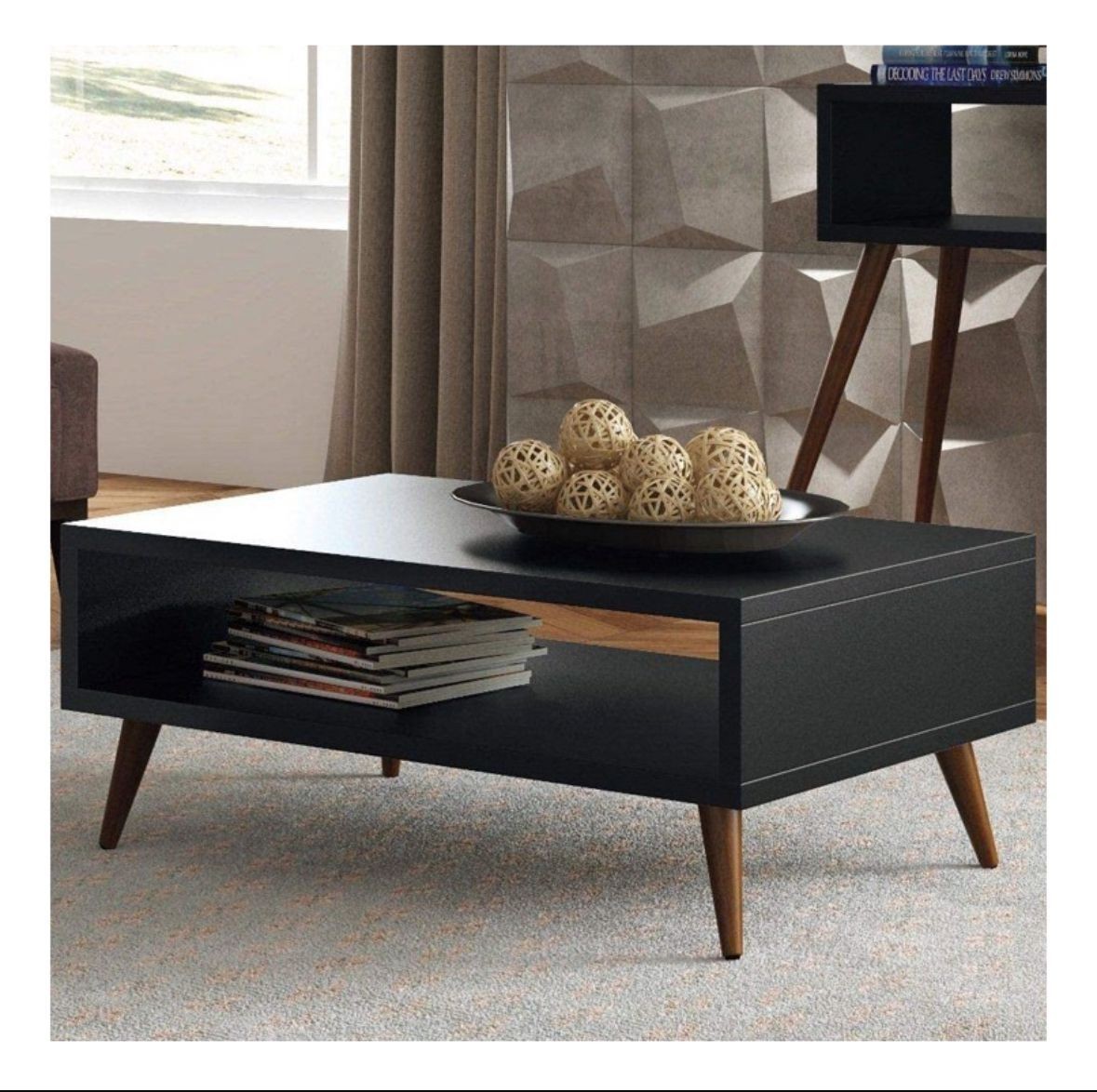 Modern black coffee table with wooden legs, displaying decorative spheres and stacked books underneath.