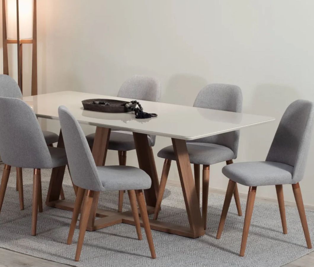 Modern dining room with a white table and six gray upholstered chairs on a light rug.